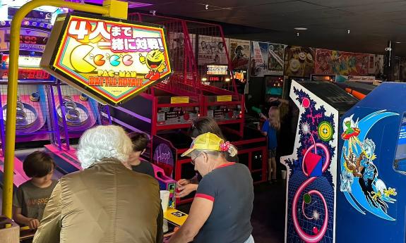 Two adults and two kids, playing PacMan at Anastasia Island's Arcade Museum