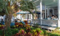 The porch and patio at a bed and breakfast nestled among greenery with guests enjoying breakfast