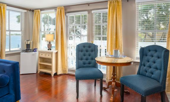 This large guest room features a full-size sofa, a dinette, a coffee corner, and views of the deck and bay through two windows