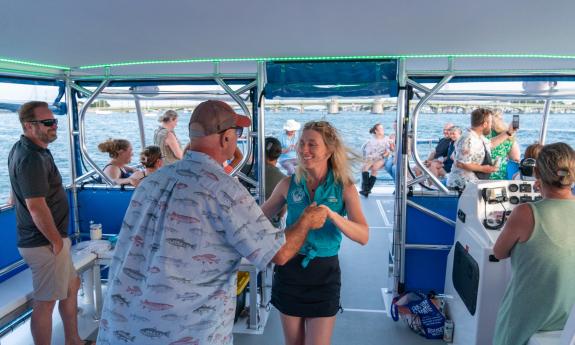 A crew member and a guest dance aboard a Florida Water Tours boat