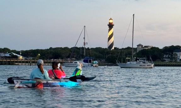 An LED kayak on the water with the Lighthouse in the distance