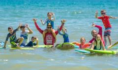 A group of surfers and instructors in the water, smiling and posing in St. Augustine, FL.