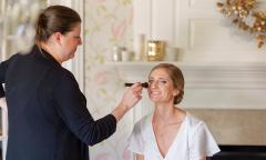 A makeup artist dabbing blush on her client's cheeks