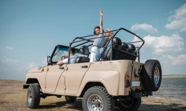 Friends driving on the beach in a tan jeep