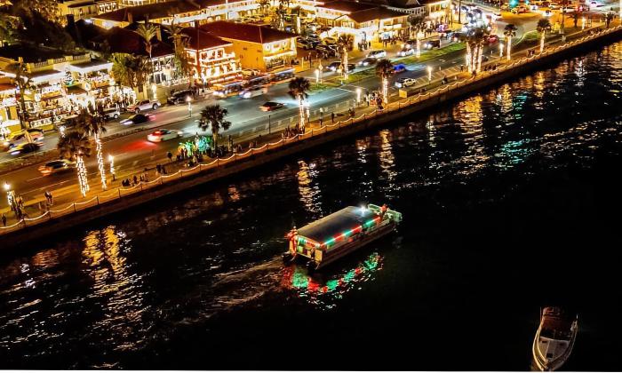 The Red Boat tour boat, decorated for the holidays, motoring along St. Augustine's bayfront and viewed from above