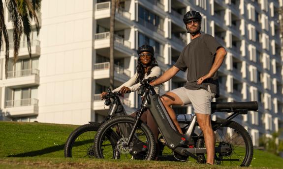 Two people on Segway e-bikes in front of a tall white building
